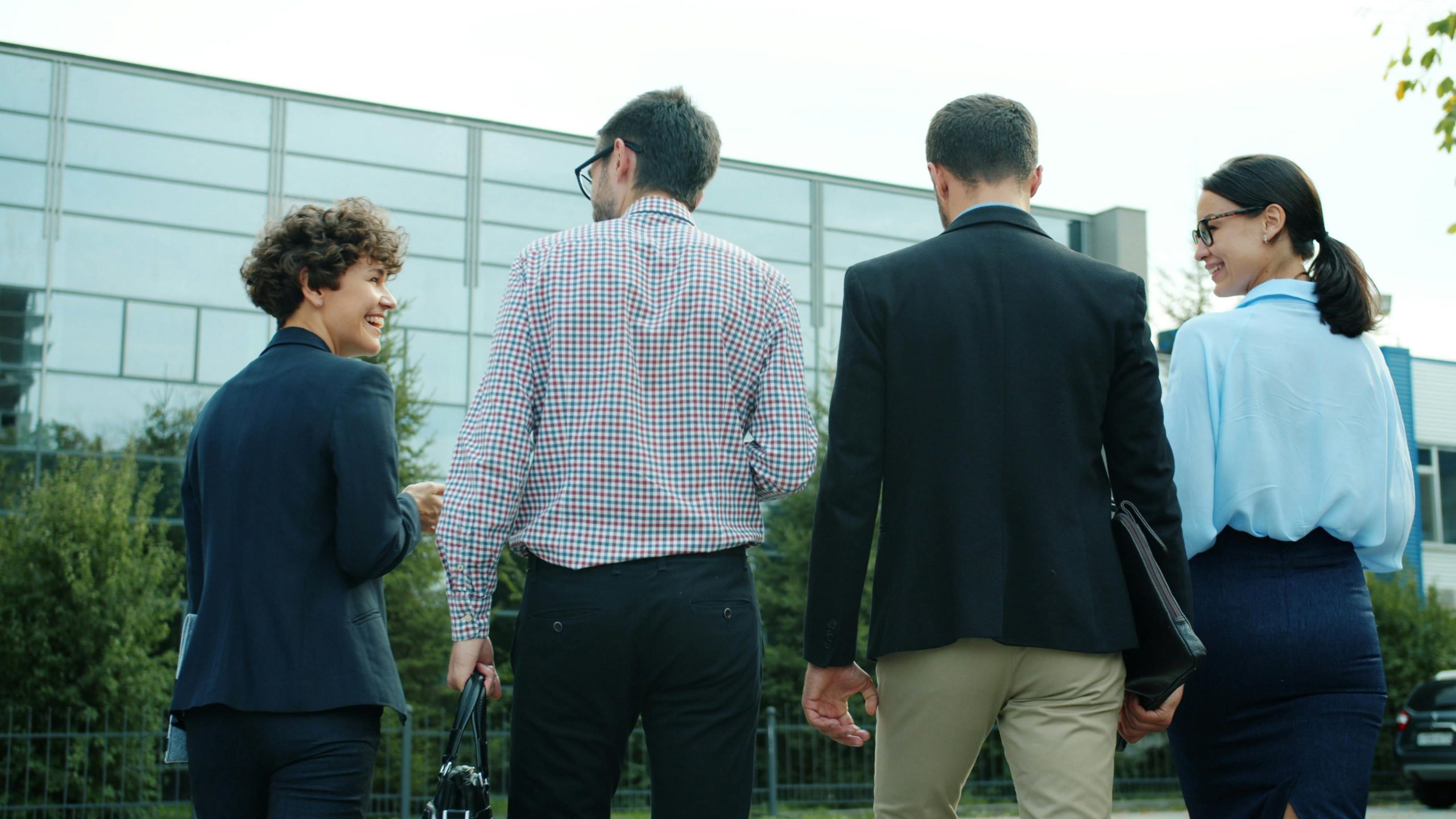 Group of business professionals walking outdoors near a modern office building.